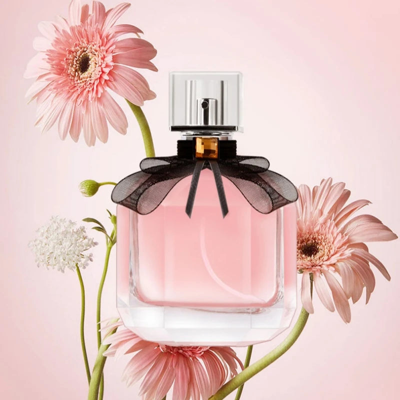 Parfum pour femmes Reverse Paris, flacon transparent rosé avec nœud noir et bouchon argenté.