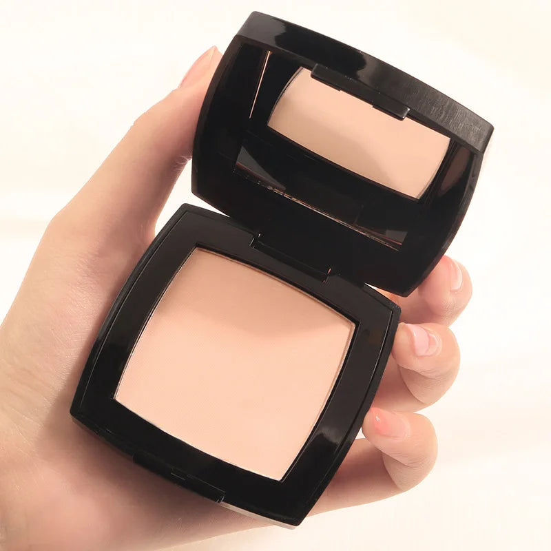 Poudre libre fixante transparente compacte, boîtier noir ouvert avec poudre beige claire
